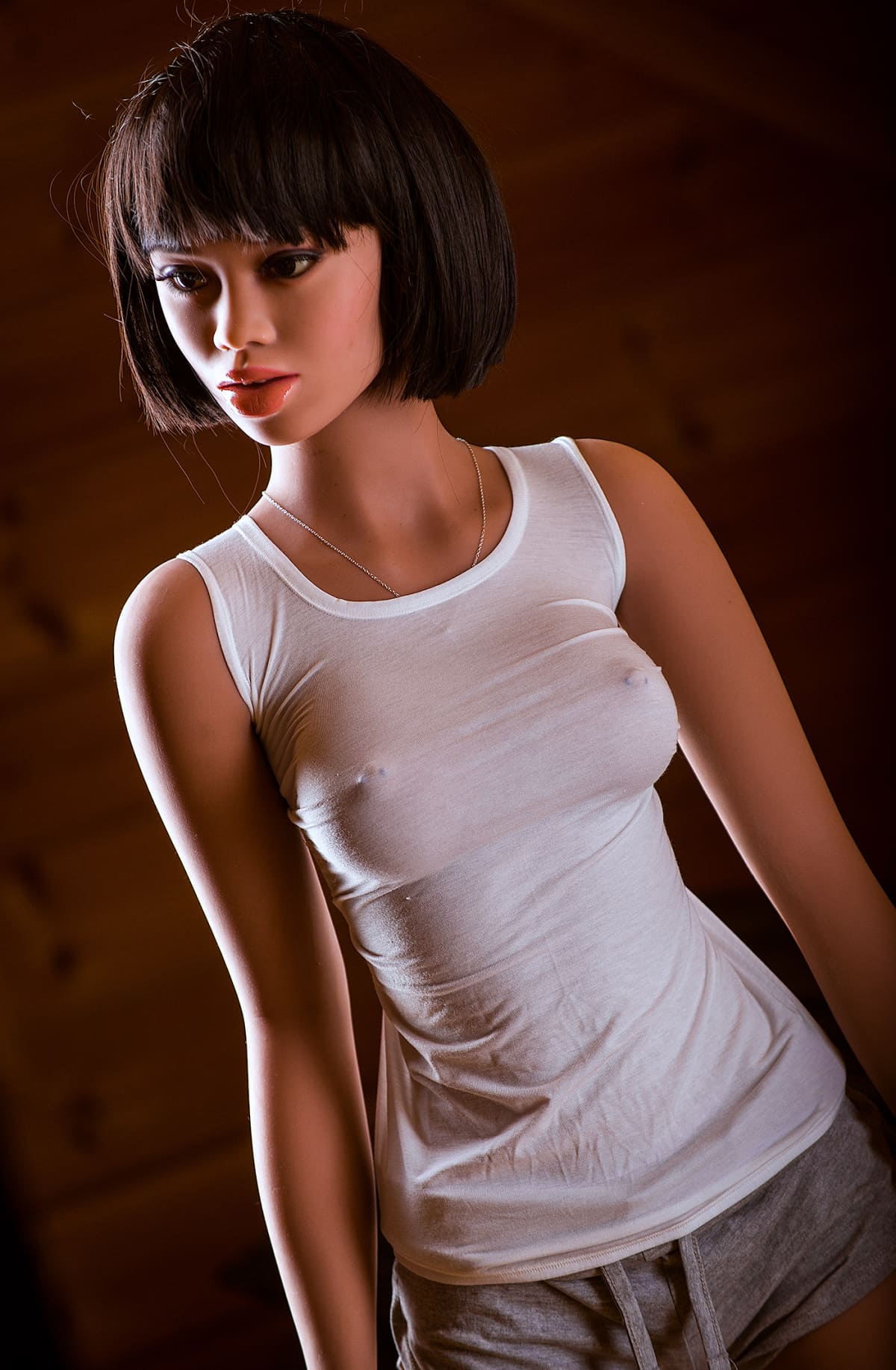 Секс-кукла Nila фото 6 - SexDolls.com.ua Секс кукла Nila в белой майке и коротких шортах смотрит в сторону
