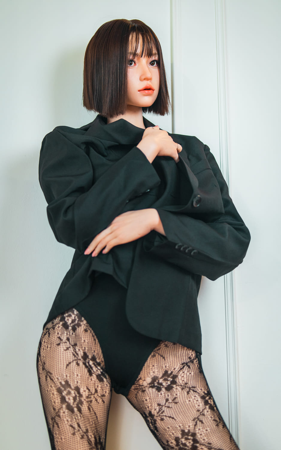 Секс-кукла Arin - фото 4 - SexDolls.com.ua Секс кукла Arin стоит в черном пиджаке и ажурных колготах